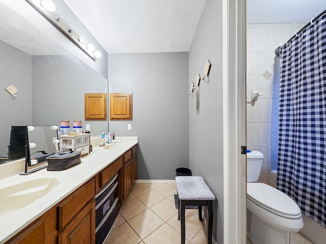 bathroom featuring toilet, tile patterned flooring, curtained shower, vanity, and a textured ceiling