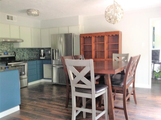 dining space with dark wood-type flooring and a notable chandelier