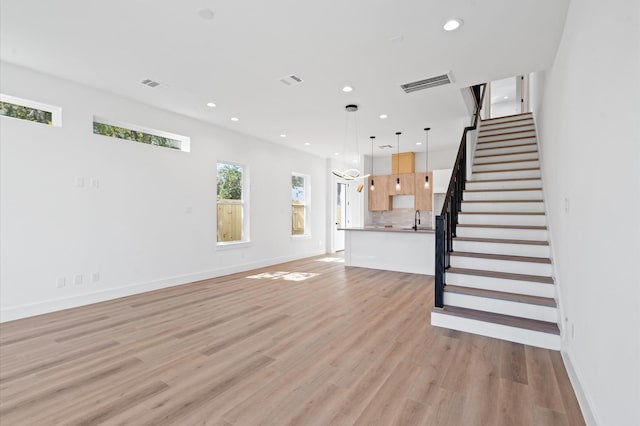 unfurnished living room with sink and light hardwood / wood-style flooring