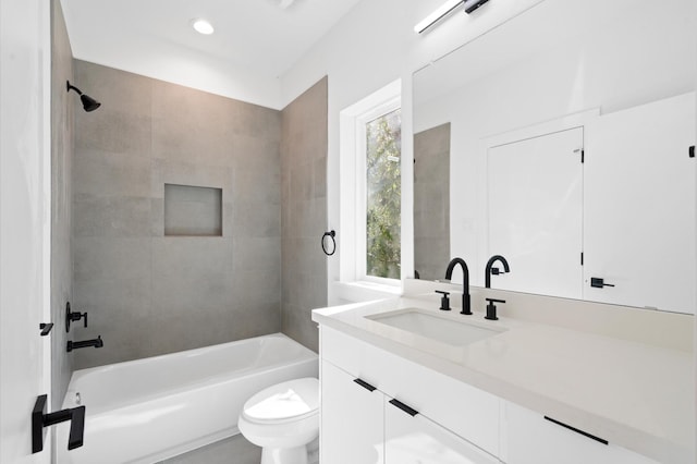 full bathroom with tiled shower / bath, vanity, and toilet