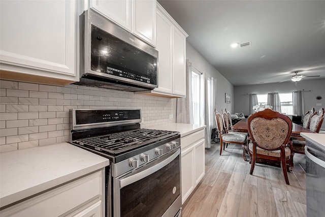 kitchen with decorative backsplash, light hardwood / wood-style flooring, stainless steel appliances, white cabinetry, and ceiling fan