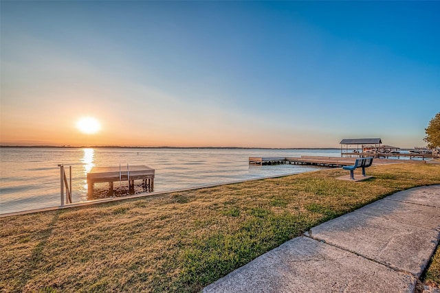 dock area with a lawn and a water view