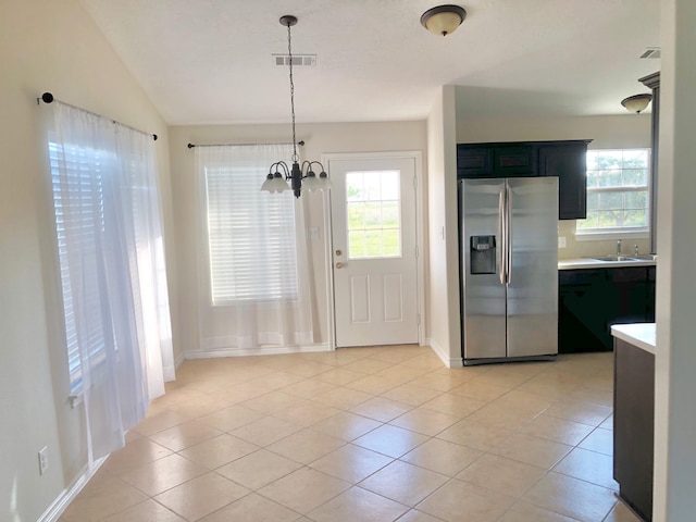 kitchen with a notable chandelier, a healthy amount of sunlight, pendant lighting, and stainless steel fridge with ice dispenser