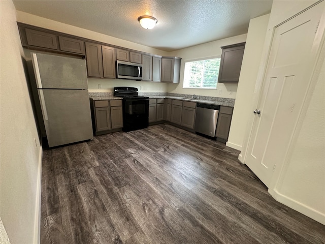 kitchen with appliances with stainless steel finishes, a textured ceiling, and dark wood-type flooring