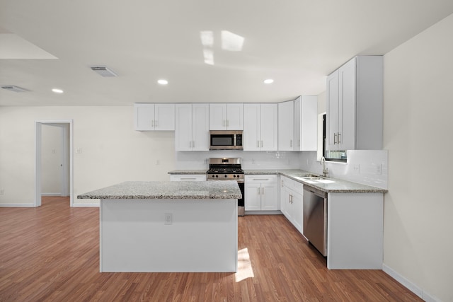 kitchen with sink, a kitchen island, white cabinetry, light hardwood / wood-style floors, and stainless steel appliances