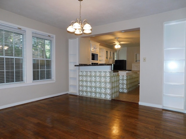 interior space featuring ceiling fan with notable chandelier and dark hardwood / wood-style flooring