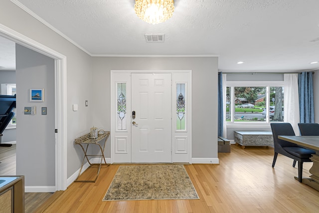 entrance foyer featuring light hardwood / wood-style floors, ornamental molding, and a textured ceiling