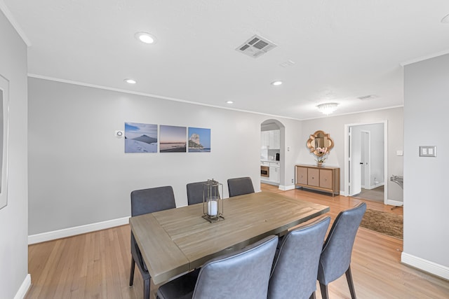 dining space featuring crown molding and light wood-type flooring