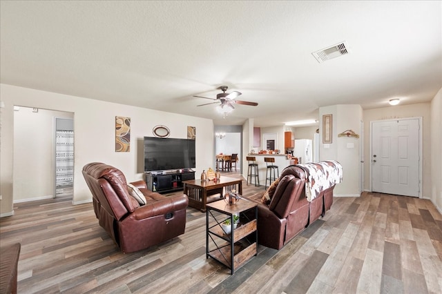 living room with hardwood / wood-style floors, a textured ceiling, and ceiling fan