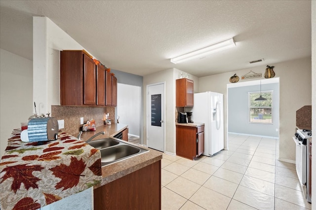 kitchen with decorative backsplash, sink, white refrigerator with ice dispenser, stainless steel range with gas stovetop, and a textured ceiling