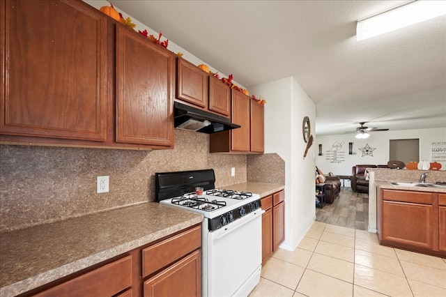 kitchen with sink, white range with gas stovetop, ceiling fan, decorative backsplash, and light tile patterned floors