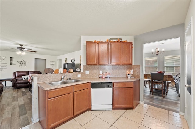 kitchen with kitchen peninsula, light wood-type flooring, dishwasher, pendant lighting, and sink