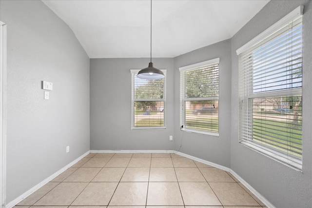 unfurnished dining area with lofted ceiling and light tile patterned floors