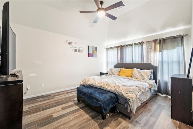 bedroom with ceiling fan, wood-type flooring, multiple windows, and vaulted ceiling