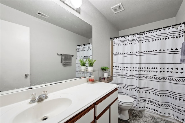 bathroom featuring vanity, a textured ceiling, toilet, and walk in shower