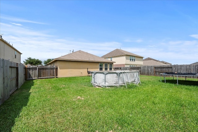 view of yard featuring a trampoline and a covered pool