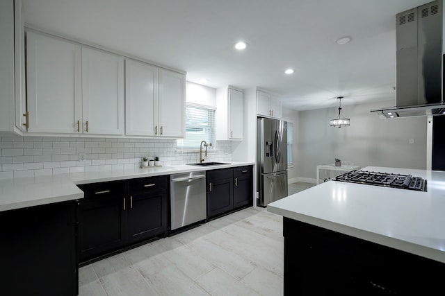 kitchen featuring white cabinets, exhaust hood, appliances with stainless steel finishes, pendant lighting, and sink