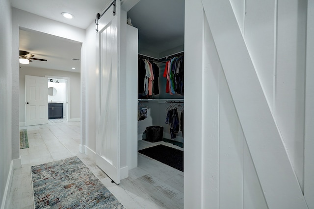 walk in closet with a barn door and ceiling fan