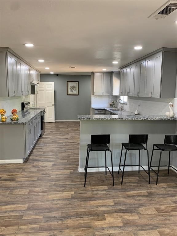 kitchen with kitchen peninsula, dark wood-type flooring, gray cabinetry, stainless steel range with electric stovetop, and sink