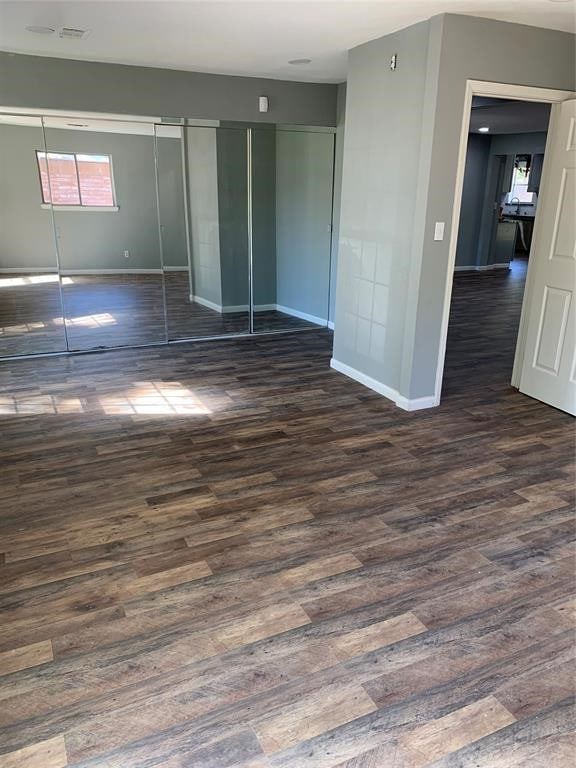 unfurnished bedroom featuring a closet and dark wood-type flooring