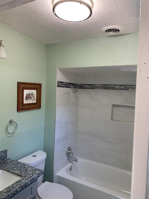 full bathroom featuring tiled shower / bath, vanity, a textured ceiling, and toilet