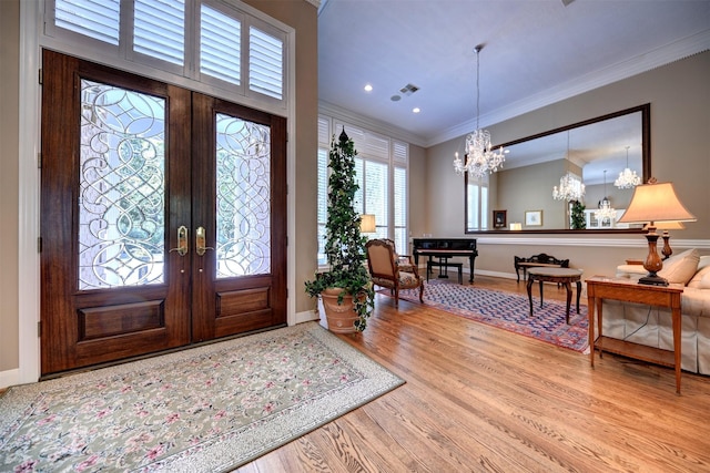 851 Elm Dr, Brenham, TX 77833 - entrance foyer featuring french doors, ornamental molding, a chandelier, wood finished floors, and baseboards