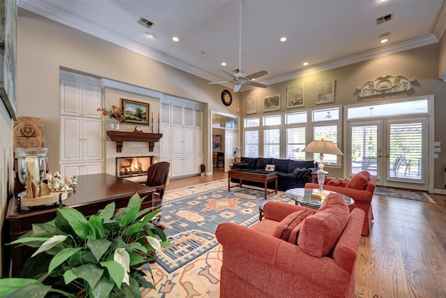 living room with ceiling fan, light hardwood / wood-style flooring, crown molding, a towering ceiling, and french doors