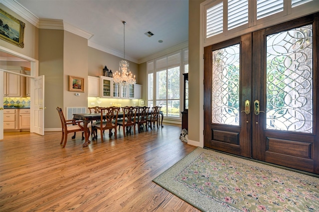 851 Elm Dr, Brenham, TX 77833 - foyer entrance featuring french doors, crown molding, a towering ceiling, a chandelier, and light wood-style floors
