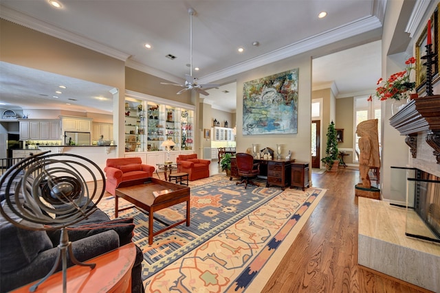 living room with crown molding, light wood-type flooring, and ceiling fan