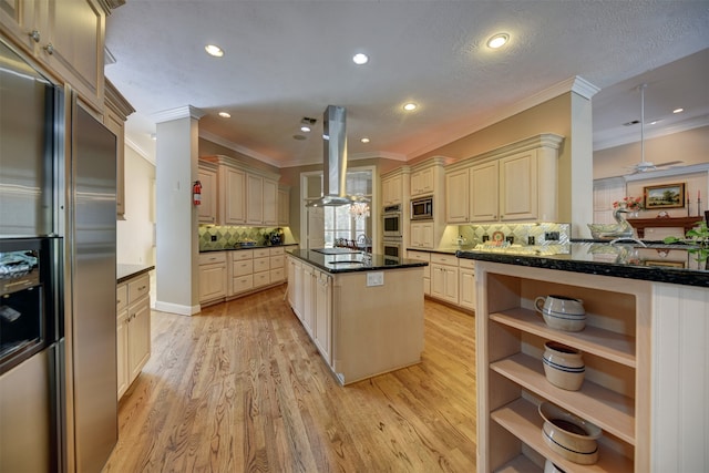 kitchen with island range hood, a kitchen island, decorative backsplash, cream cabinets, and built in appliances