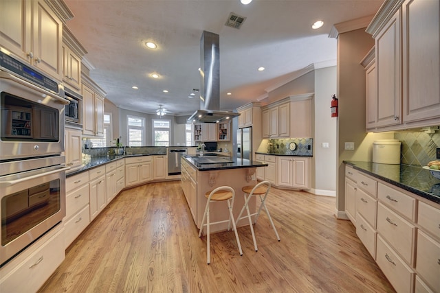 kitchen featuring decorative backsplash, light wood-type flooring, stainless steel appliances, crown molding, and a center island