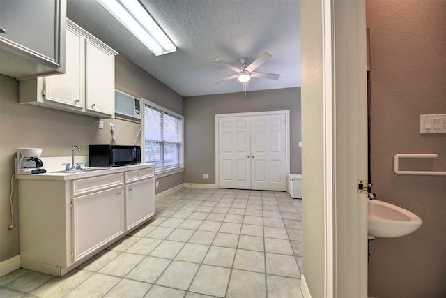 851 Elm Dr, Brenham, TX 77833 - kitchen with black microwave, a sink, ceiling fan, light countertops, and white cabinets