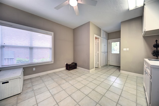 kitchen with white cabinetry, a textured ceiling, light tile patterned floors, and ceiling fan