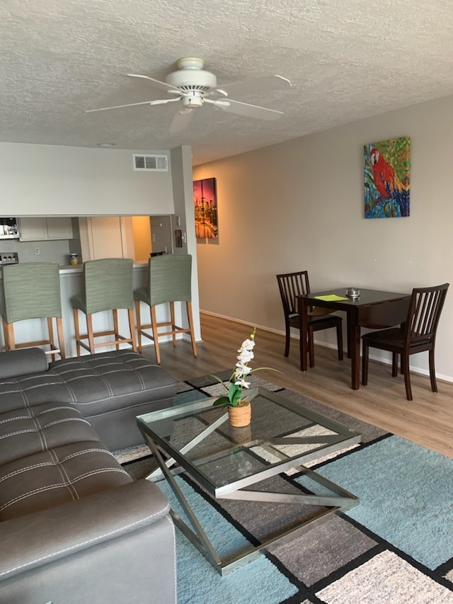 living room featuring hardwood / wood-style floors, a textured ceiling, and ceiling fan