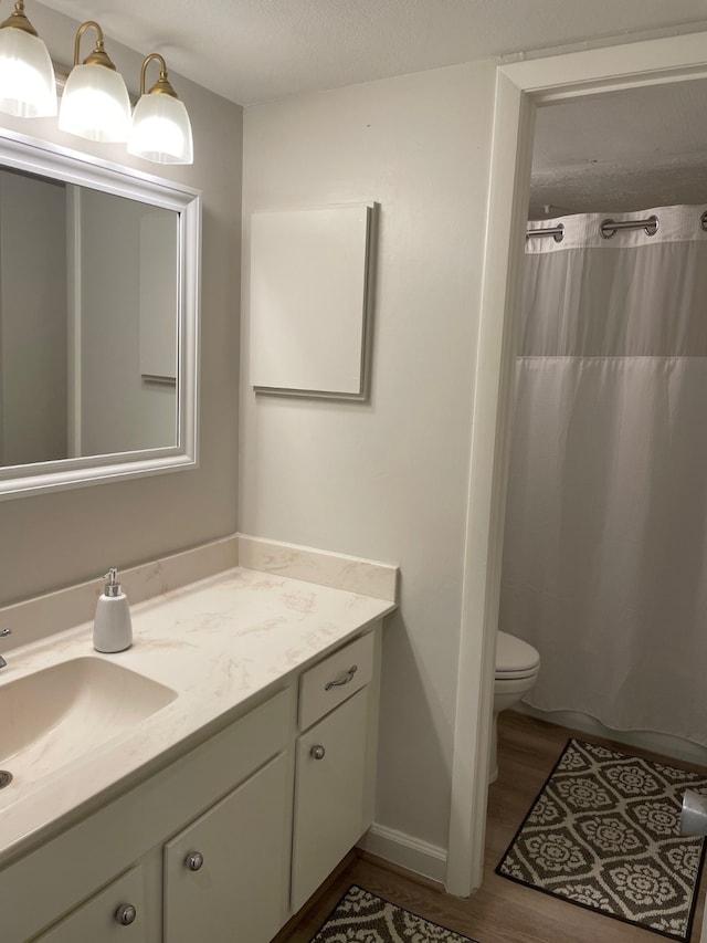 bathroom with wood-type flooring, a textured ceiling, toilet, a shower with curtain, and vanity