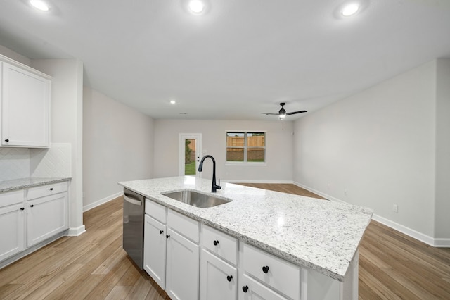 kitchen featuring sink, light wood-type flooring, an island with sink, stainless steel dishwasher, and white cabinets