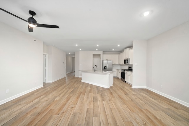 kitchen featuring white cabinetry, light hardwood / wood-style floors, appliances with stainless steel finishes, and a kitchen island with sink