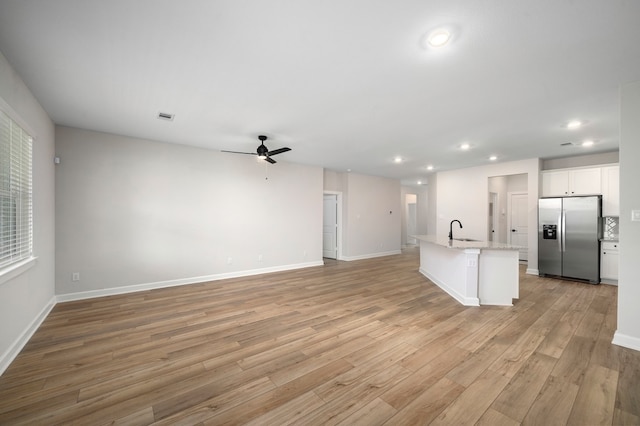 unfurnished living room with sink, light hardwood / wood-style flooring, and ceiling fan