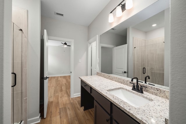 bathroom with vanity, hardwood / wood-style flooring, a shower with shower door, and ceiling fan