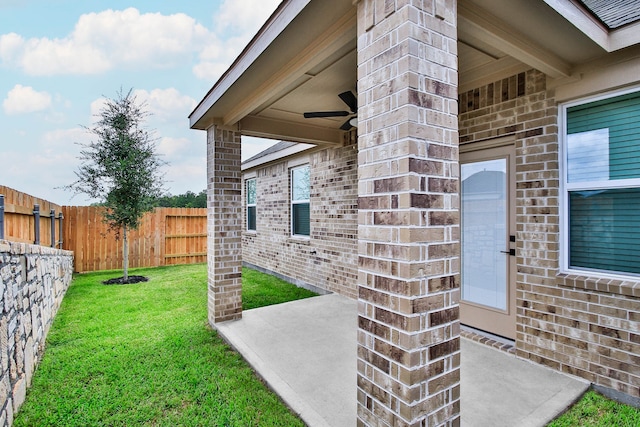 view of exterior entry with a patio area, a lawn, and ceiling fan