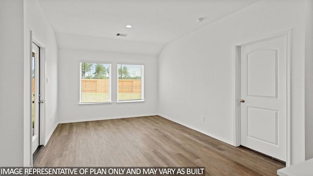 empty room with wood-type flooring and lofted ceiling