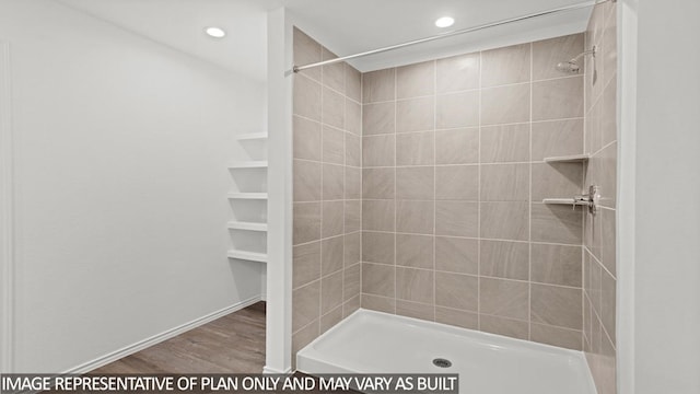 bathroom with hardwood / wood-style floors and a tile shower