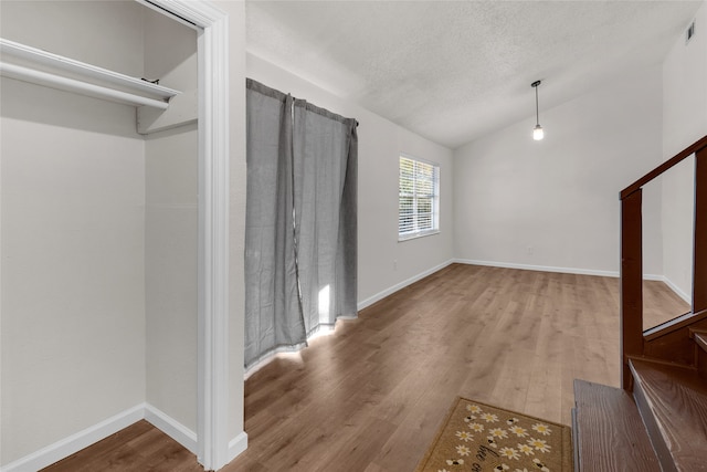 unfurnished living room featuring a textured ceiling, hardwood / wood-style flooring, and vaulted ceiling