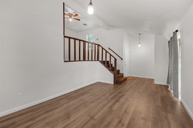 interior space featuring ceiling fan, wood-type flooring, and vaulted ceiling with beams