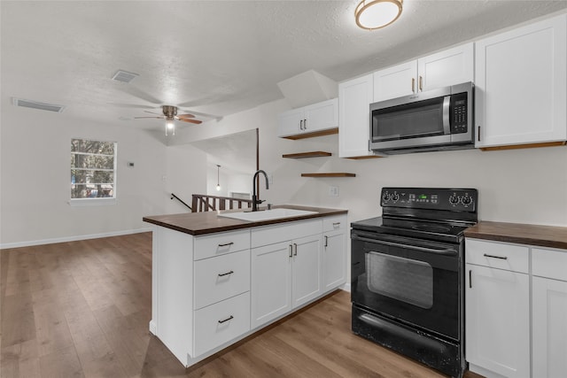 kitchen featuring black range with electric cooktop, white cabinets, and light wood-type flooring