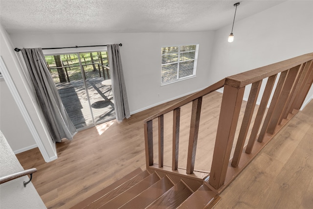 stairs with hardwood / wood-style flooring, a textured ceiling, and a wealth of natural light