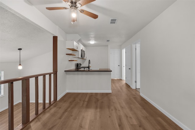 bar with pendant lighting, ceiling fan, light wood-type flooring, and white cabinets