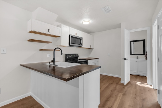 kitchen featuring kitchen peninsula, white cabinets, sink, and electric range