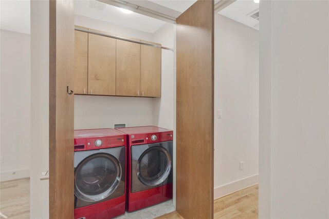 laundry room featuring cabinets, light wood-type flooring, and independent washer and dryer