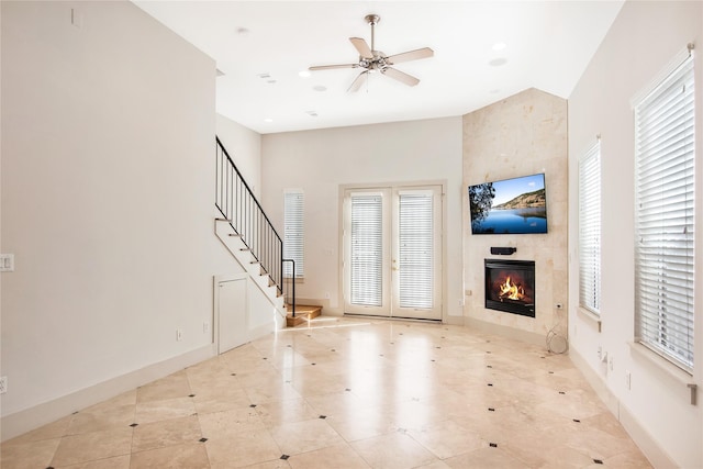 unfurnished living room featuring ceiling fan, a healthy amount of sunlight, light tile patterned floors, and a fireplace